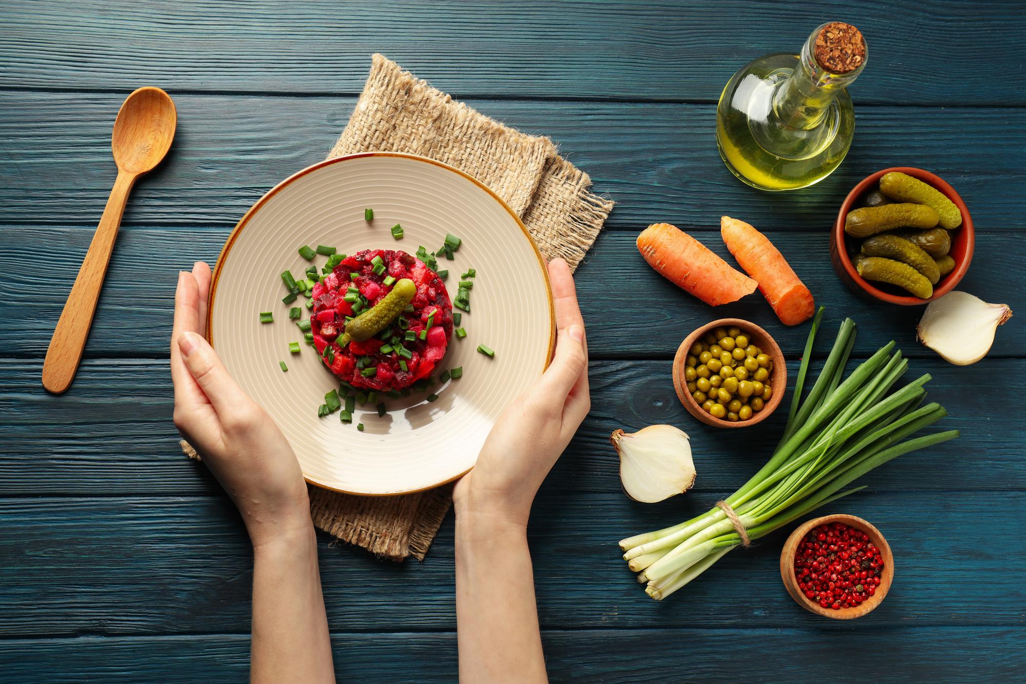 Chef arranging colorful plated dish on wooden table